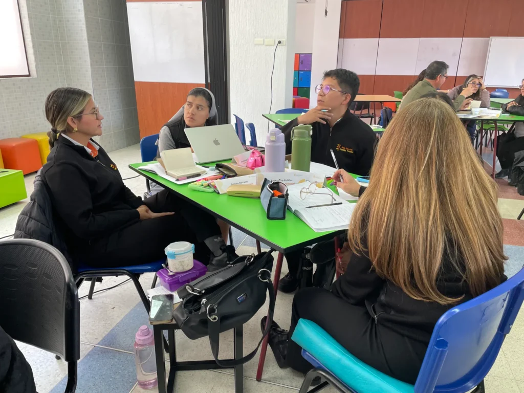 Equipo docente compartiendo ideas y materiales durante la jornada de formación en el Colegio Sagrada Familia de Nazaret de Bogotá.